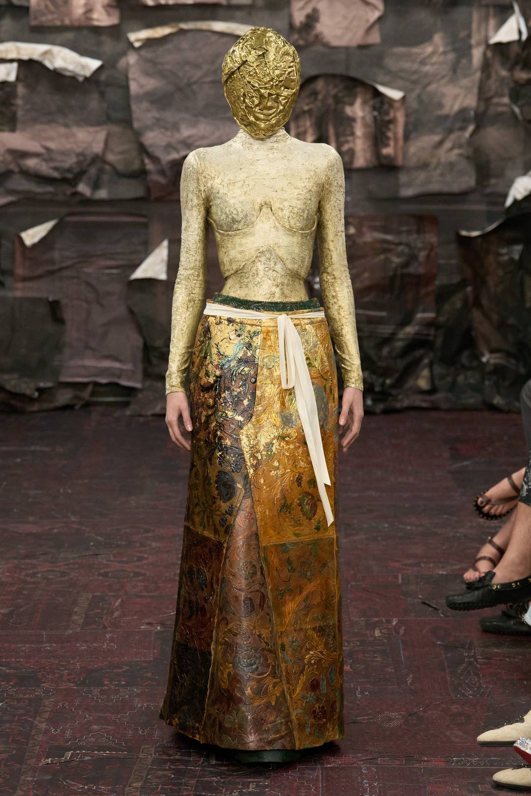 Look 13: Corsetto con sottogonna e grembiule ricavati da pantaloni di pelle, dipinti a mano e decorati con foglia oro.