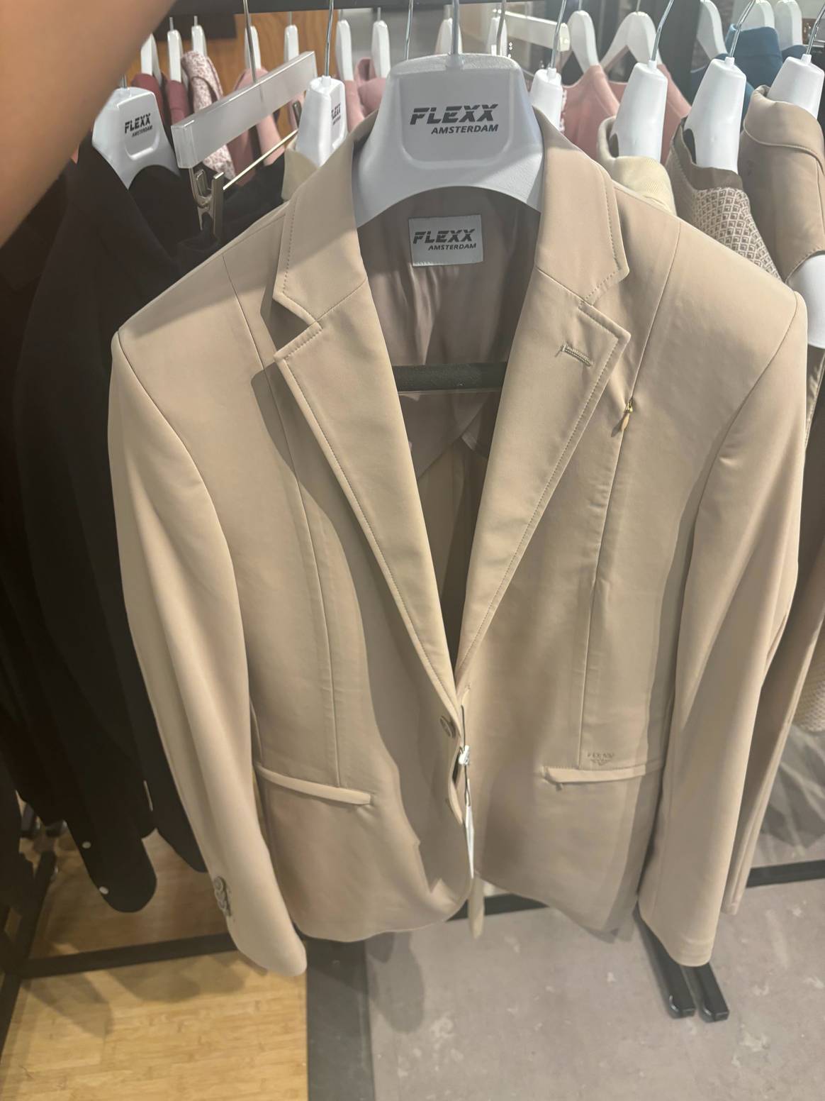 De vertegenwoordiger van Flexx Amsterdam laat een blazer zien van stretchstoffen.