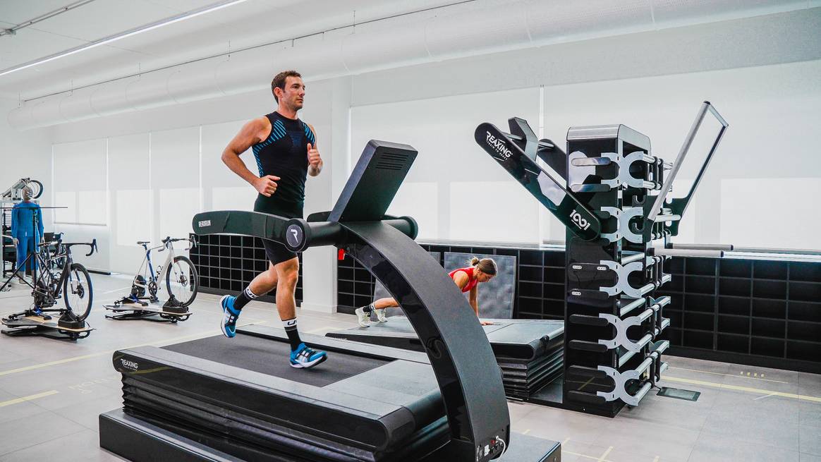 Athletes on treadmills and bicycle stands and humanoid robots (in the background) in the Brain Unit