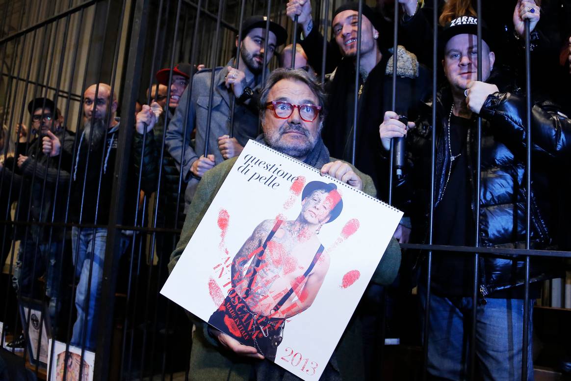 Italian Photographer Oliviero Toscani holds his new 2013 calendar dedicated to tattooed people as he poses with his models on January 10, 2013 in Florence.