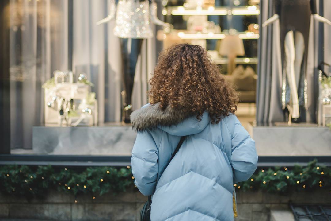 Mujer frente al escaparate de una tienda de moda.