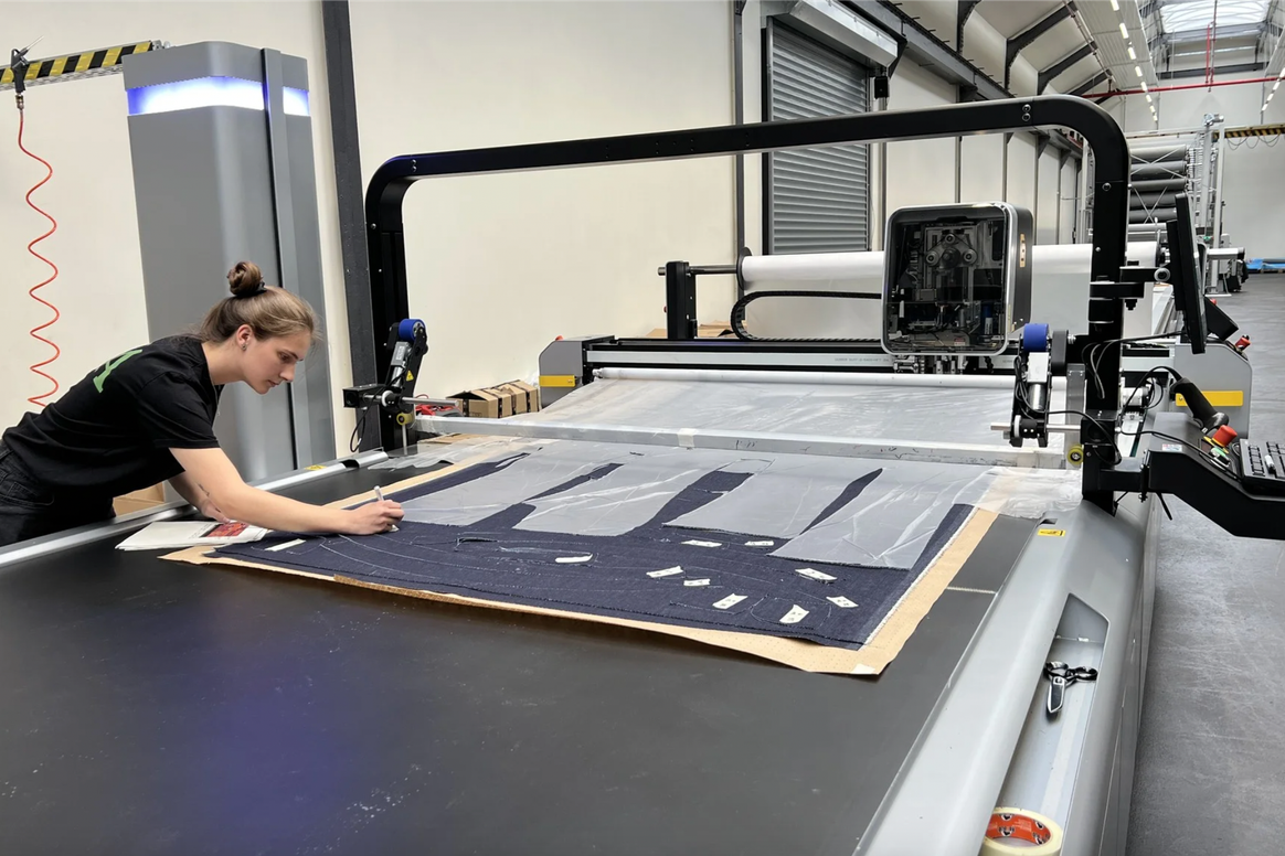 The fabric are pulled from the warehouse and then automatically laid and cut. The Setec machine also has a ride-on device for the personnel. In cooperation with the Niederrhein University of Applied Sciences, C&A is trying to reduce the waste from cutting the fabric and to recycle it in the future. Yarns could be made from the fabric scraps, for example.Credits: C&A FIT ©2022 C. Niehlinger