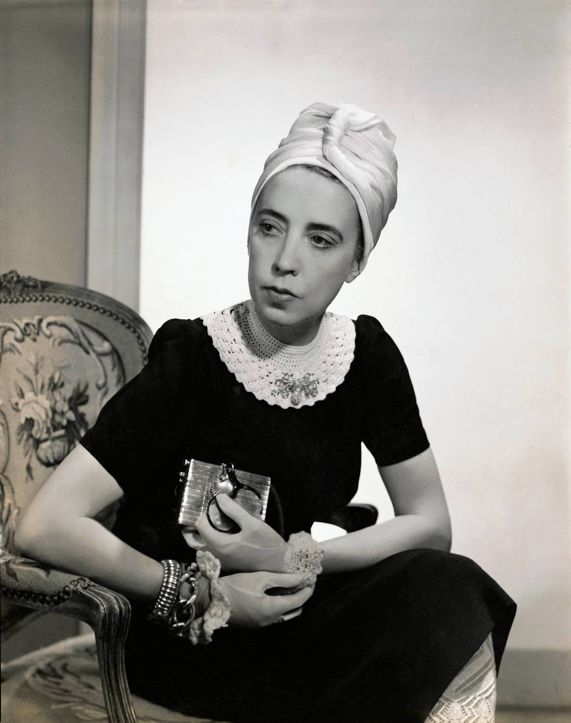 Vogue 1940; Designer Elsa Schiaparelli wearing black silk dress with crocheted collar of her own design and a turban