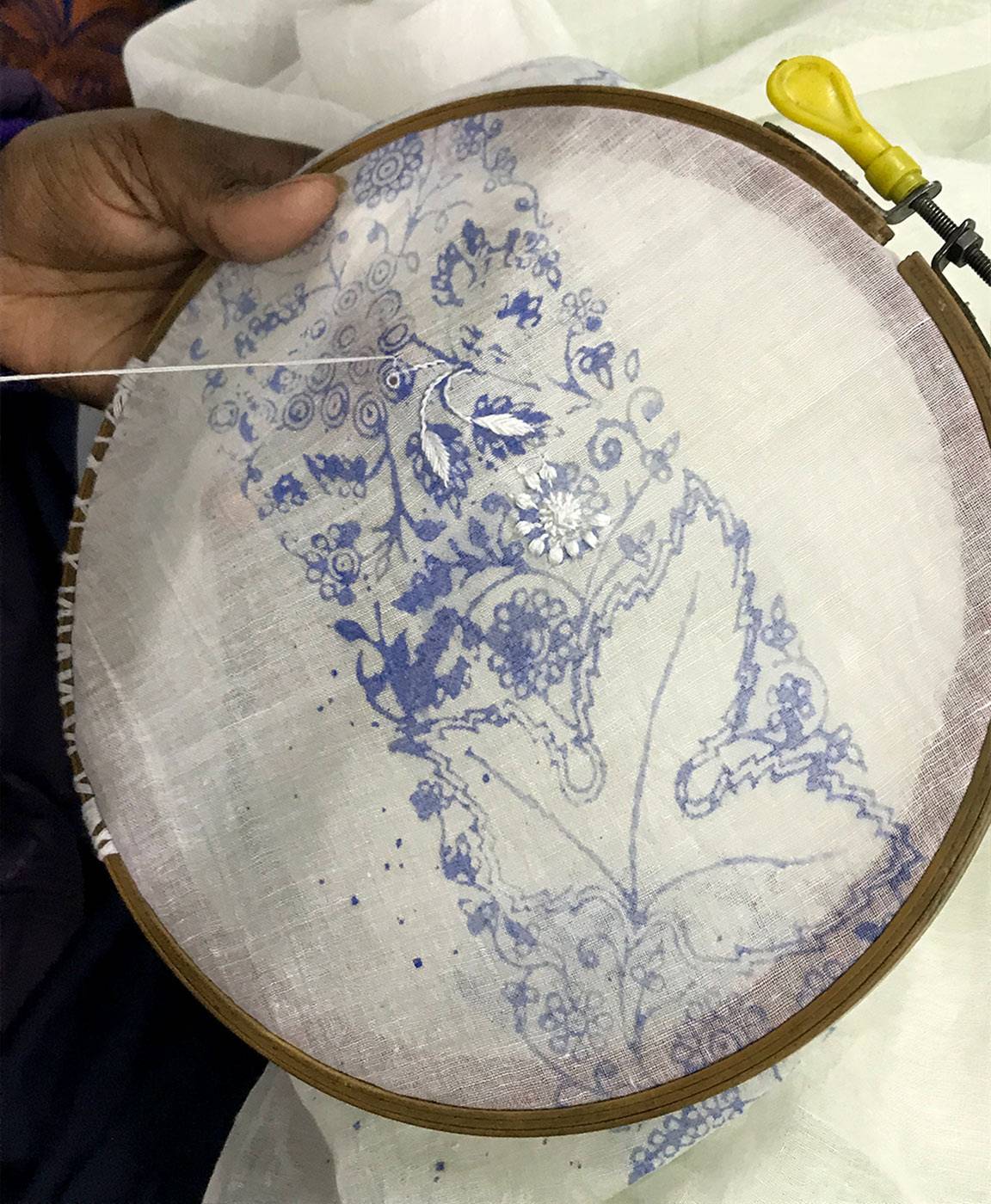 Eine Kunsthandwerkerin bei der Arbeit an einer zarten Chikankari-Stickerei