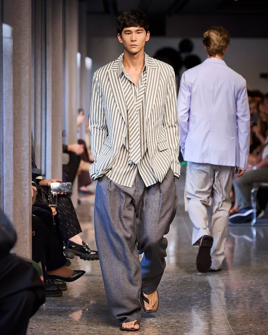 Amplidão levada ao extremo na calça, composta com camisa e paletó listrado