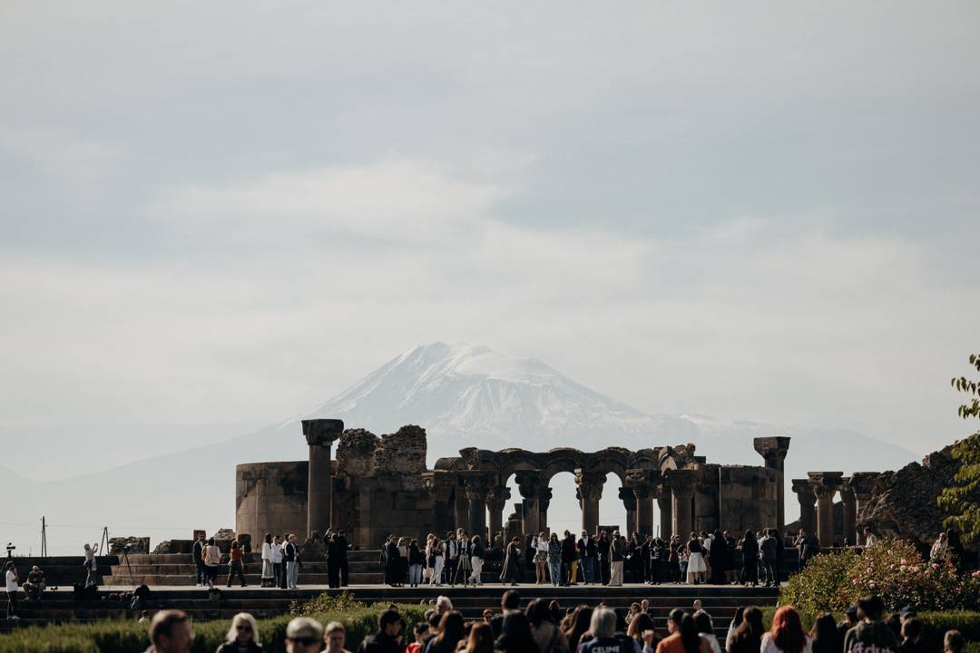 Gli invitati alla sfilata di Ruzanē tra le rovine della cattedrale di Zvartnots, con il monte Ararat sullo sfondo.