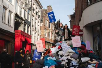 Kalverstraat geblokkeerd met berg afgedankte kleding tijdens modeprotest