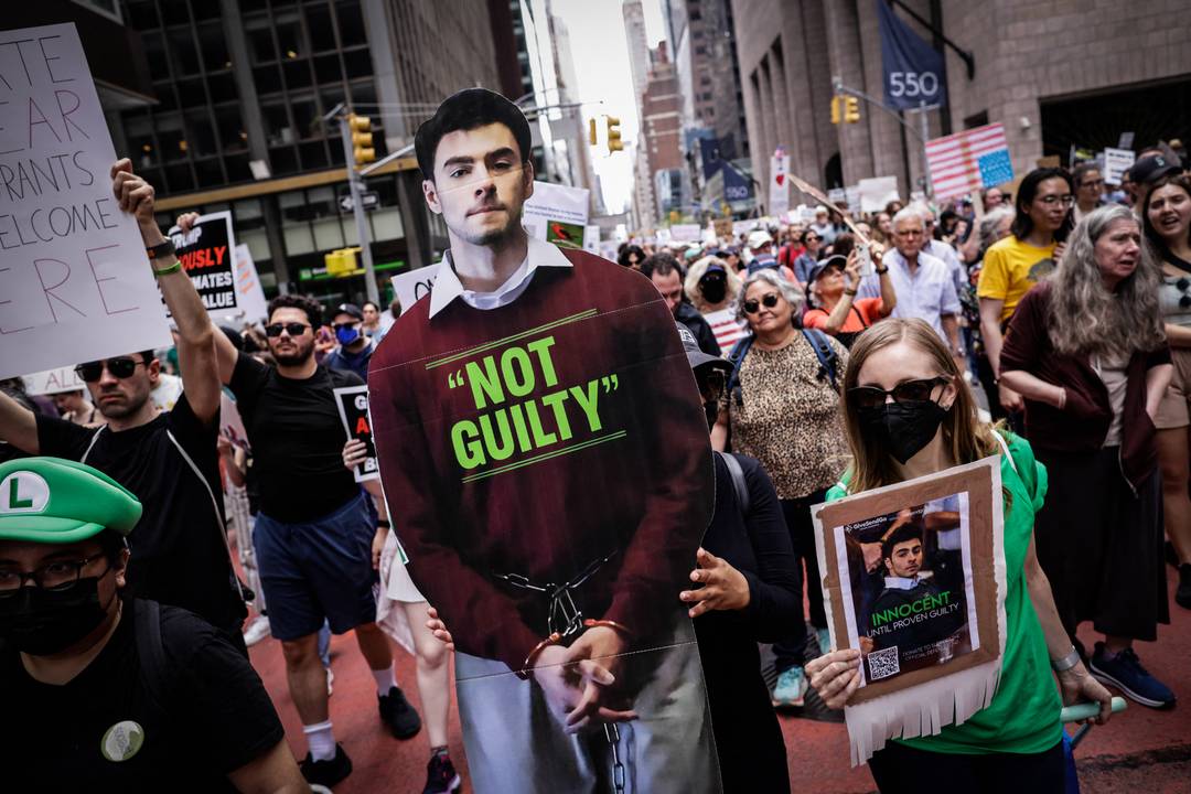 Een vrouw houdt een bord vast met de afbeelding van Luigi Mangione, terwijl andere mensen spandoeken omhoog houden tijdens een demonstratie met de titel 'Bescherm migranten, bescherm de planeet', in New York, op 19 april 2024.