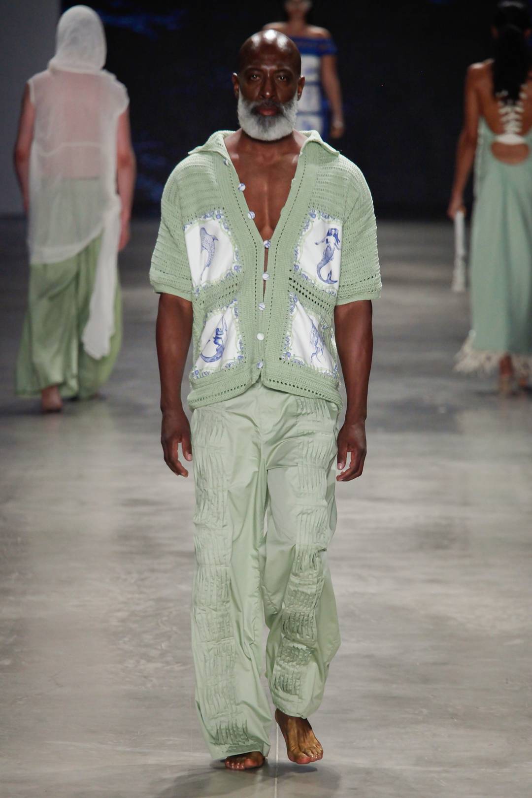 A camisa em crochê tem aplicação de tecidos, enquanto as calça vem com trabalho de pregas pequenas como nervuras em Santa Resistência